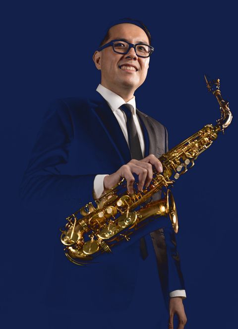 Julian Chan, smiling, holding his alto saxophone.